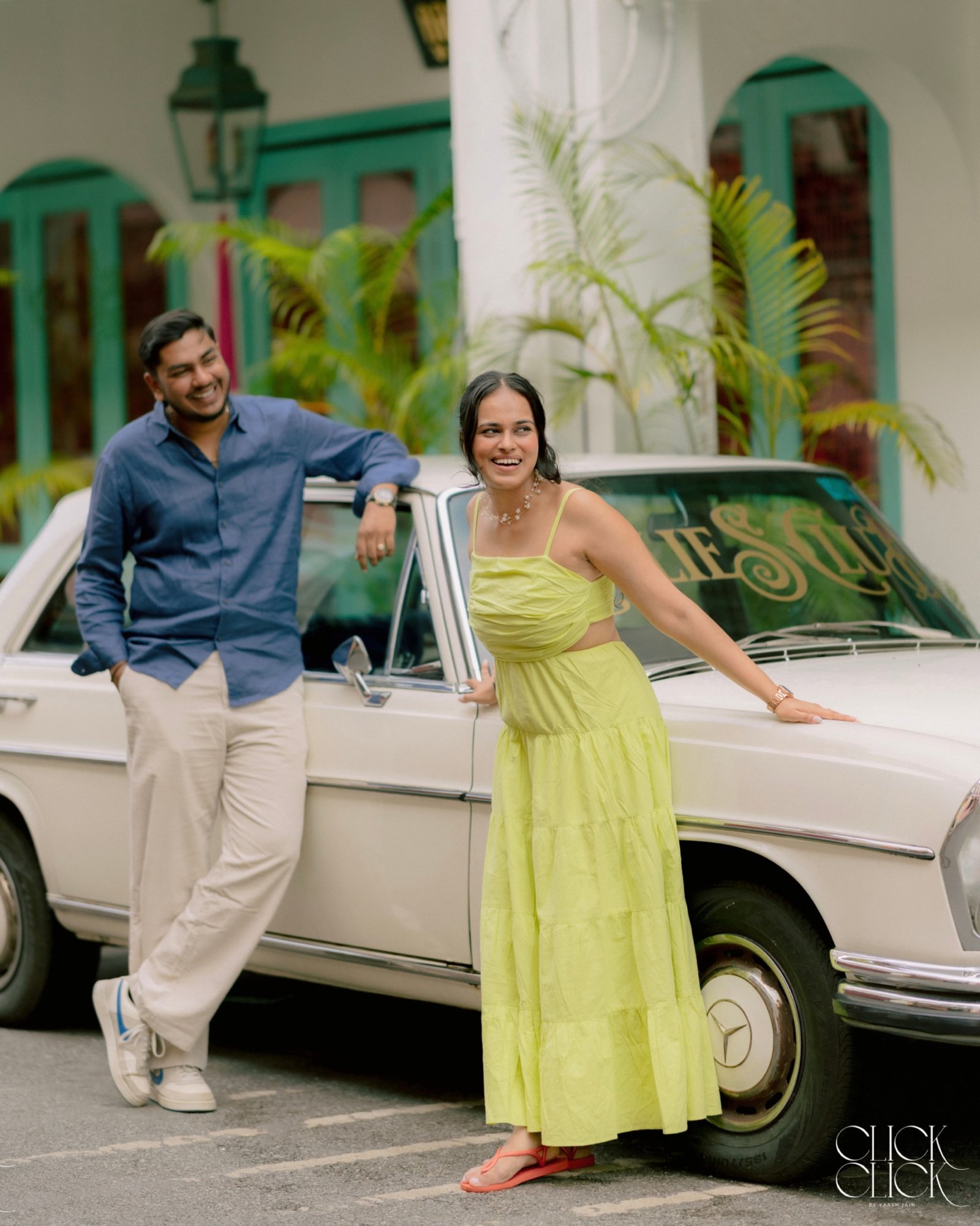 A smiling couple posing beside a white classic car